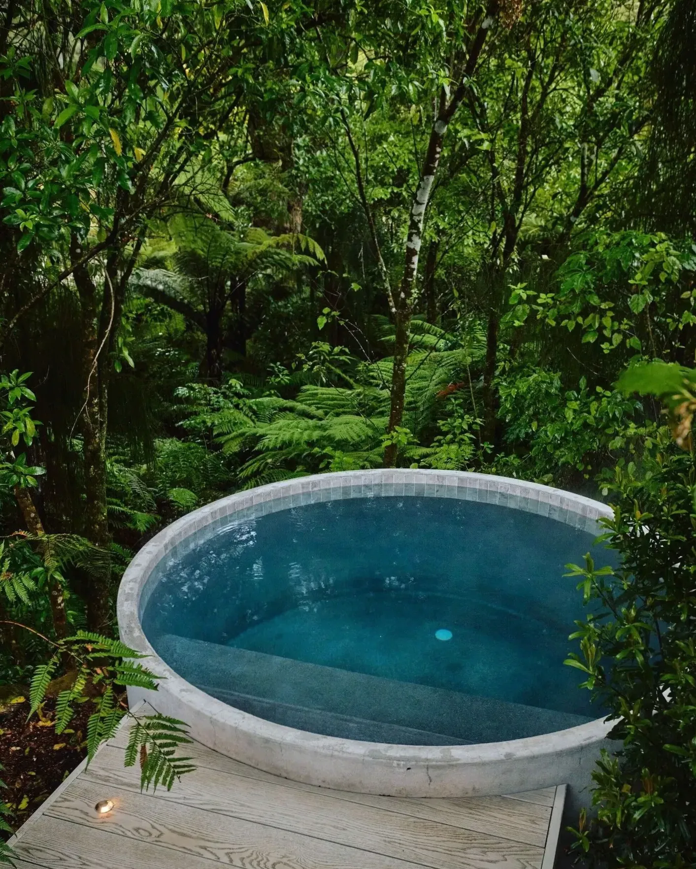 Stone-lined spa pool with candles and mountain light at Happymotion